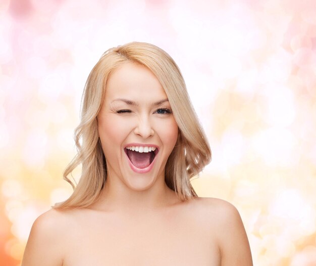 Photo concept de santé et de beauté - belle femme aux longs cheveux ondulés avec un clin de œil