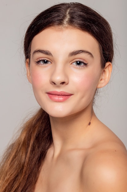 Concept de santé et de beauté - Belle jeune femme avec une peau propre et fraîche touche son propre visage. Traitement facial . Cosmétologie , beauté et spa .