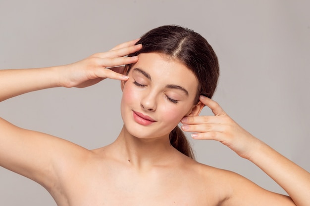 Concept de santé et de beauté - Belle jeune femme avec une peau propre et fraîche touche son propre visage. Traitement facial . Cosmétologie , beauté et spa .