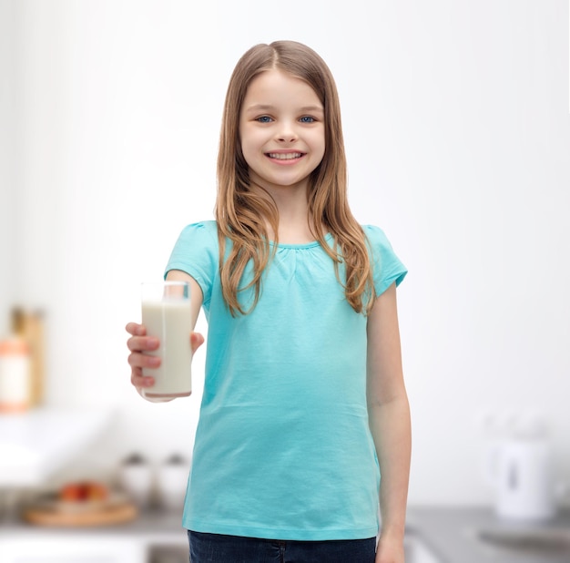 concept santé et beauté - petite fille souriante donnant un verre de lait