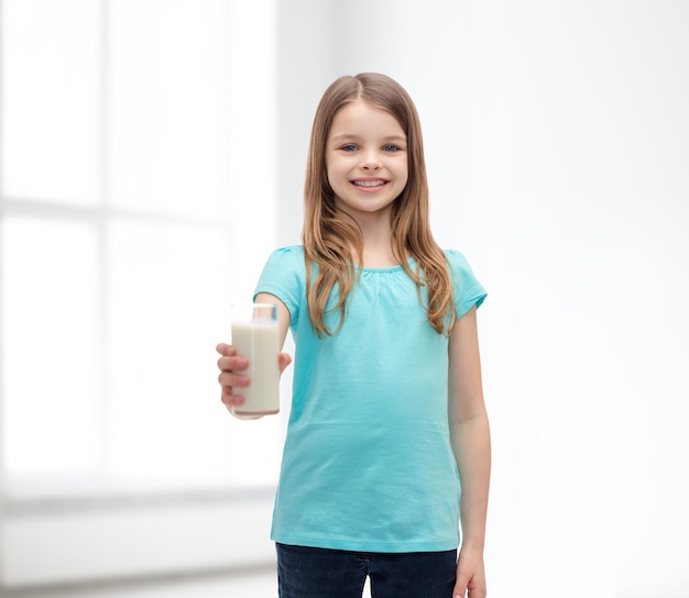 concept santé et beauté - petite fille souriante donnant un verre de lait