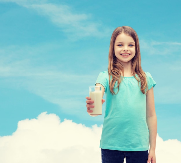 concept santé et beauté - petite fille souriante donnant un verre de lait