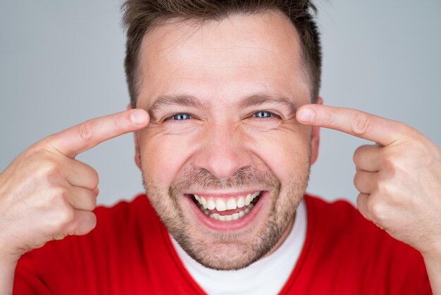 Concept de santé et de beauté souriant jeune bel homme pointant vers les yeux