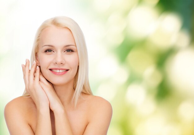 Photo concept de santé et de beauté - visage et mains de femme heureuse