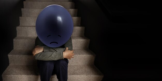 Photo concept de santé mentale une anxiété stressée une personne déprimée avec un ballon assise sur l'escalier négatif