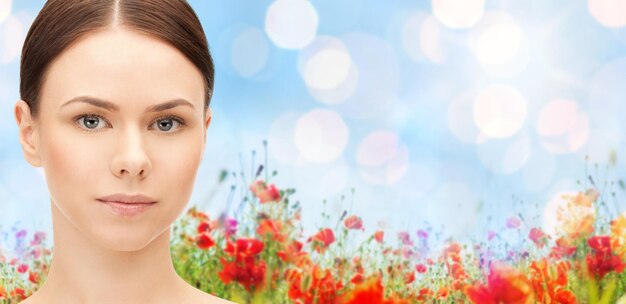 concept de santé, de personnes et de beauté - beau visage de jeune femme sur fond de champ de pavot