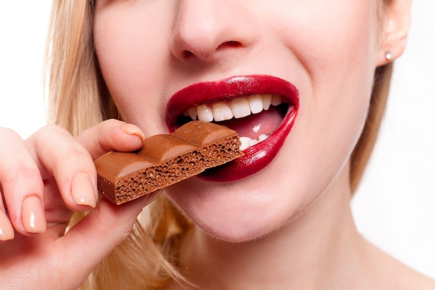 Concept de santé, de personnes, de nourriture et de beauté - Belle adolescente souriante mangeant du chocolat. Portrait de belle femme tenant une barre de chocolat.