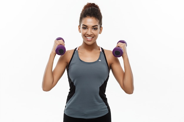 Concept de santé et de remise en forme - Belle femme africaine américaine en entraînement de vêtements de fitness avec haltère. Isolé sur fond blanc