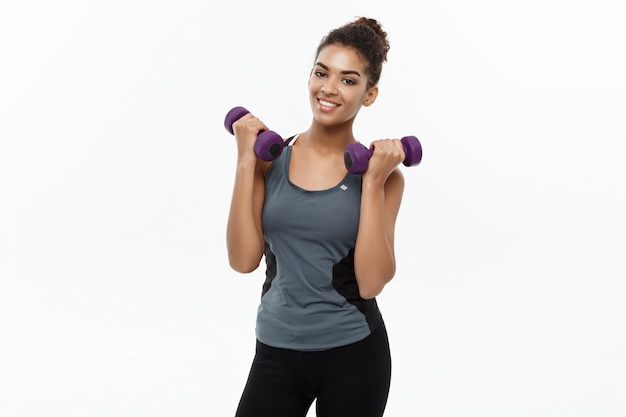 Concept de santé et de remise en forme - Belle femme africaine américaine en entraînement de vêtements de fitness avec haltère. Isolé sur fond blanc