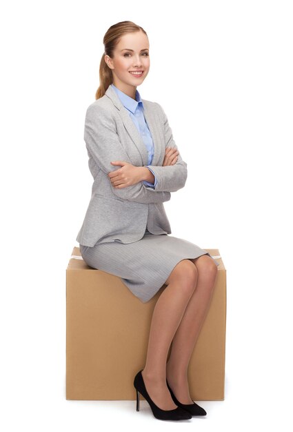 concept de service d'affaires et de livraison - femme souriante assise sur une boîte en carton