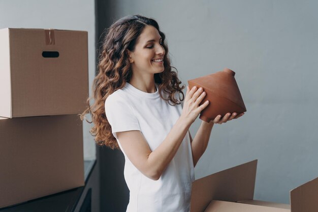 Concept de service de relocalisation et de livraison Bonne fille déballant des boîtes en carton et tenant le vase