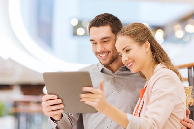 concept shopping, technologie et personnes - couple heureux avec tablette pc prenant selfie dans un centre commercial ou un centre d'affaires