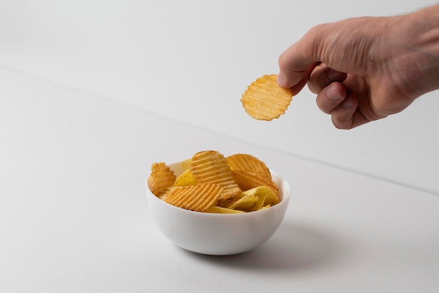 Concept simple de la main de la malbouffe choisir une seule chips de pomme de terre dans un bol