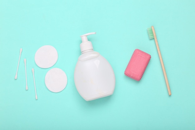 Concept de soins de beauté d'hygiène Brosse à dents de savon et bouteille de crème avec tampons sur fond bleu