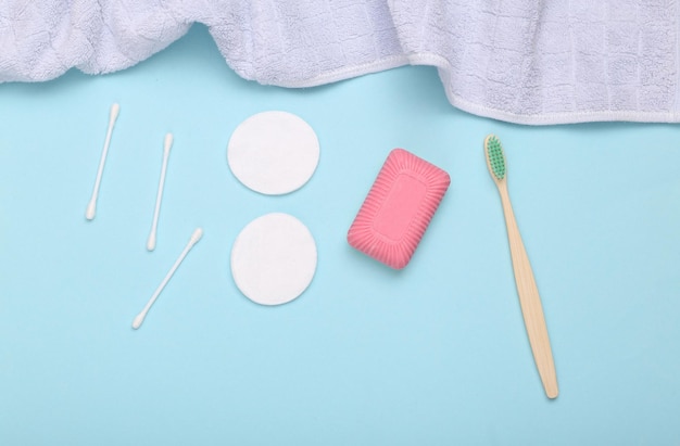 Concept de soins de beauté hygiène Savon brosse à dents tampons de coton et bâtons avec serviette sur fond bleu