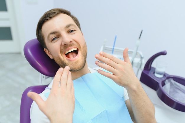 Concept de soins dentaires Beau jeune homme au cabinet du dentiste