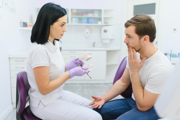 Concept de soins dentaires Beau jeune homme au cabinet du dentiste