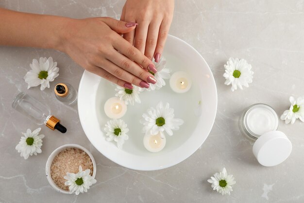 Concept de soins des mains avec des cosmétiques sur fond texturé gris