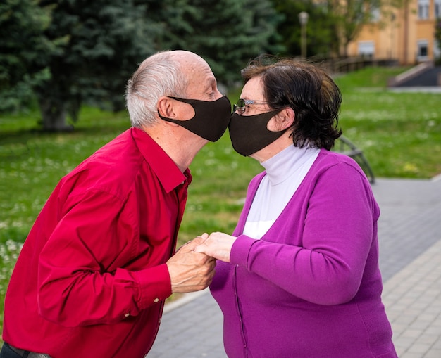 Concept de soins de santé. Couple de personnes âgées dans des masques protecteurs s'embrasser dans le parc