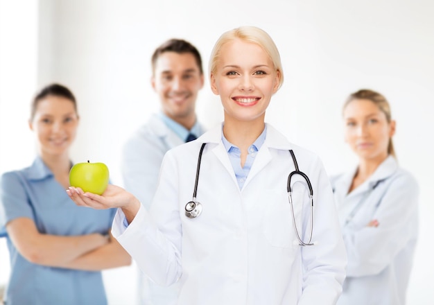 concept de soins de santé et de médecine - femme médecin souriante avec stéthoscope et pomme verte