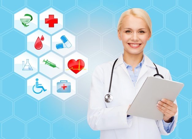 concept de soins de santé, de médecine, de personnes, de technologie et de symboles - souriante jeune femme médecin ou infirmière avec tablette pc sur icônes médicales et fond bleu