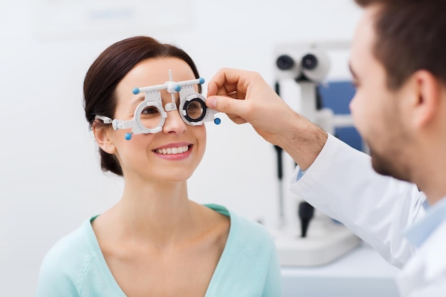 concept de soins de santé, de médecine, de personnes, de vision et de technologie - optométriste avec cadre d'essai vérifiant la vision du patient à la clinique ophtalmologique ou au magasin d'optique