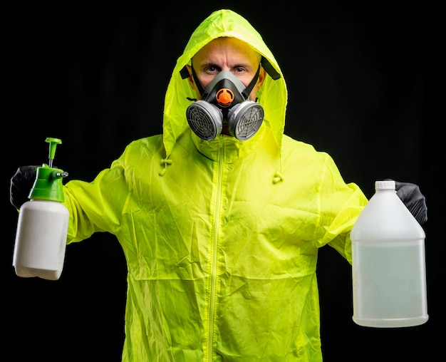 Concept de soins de santé et médical. Homme en respirateur de protection et gants tenant des bouteilles de liquide désinfectant sur fond noir