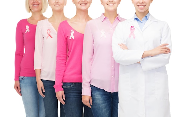 concept de soins de santé, de personnes et de médecine - gros plan de femmes souriantes en chemises vierges avec des rubans roses de sensibilisation au cancer du sein sur fond blanc