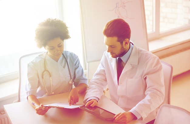 Photo concept de soins de santé, de personnes, de technologie et de médecine - médecin et infirmière avec ordinateur tablette et presse-papiers se réunissant et discutant de quelque chose à l'hôpital