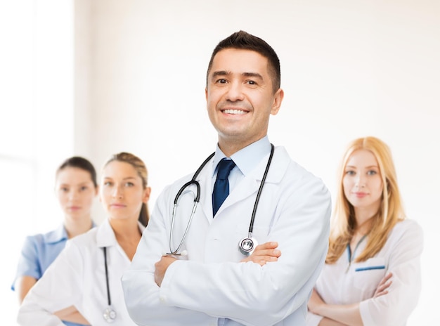 concept de soins de santé, de profession, de personnes et de médecine - médecin de sexe masculin souriant en blouse blanche sur un groupe de médecins à l'arrière-plan de l'hôpital