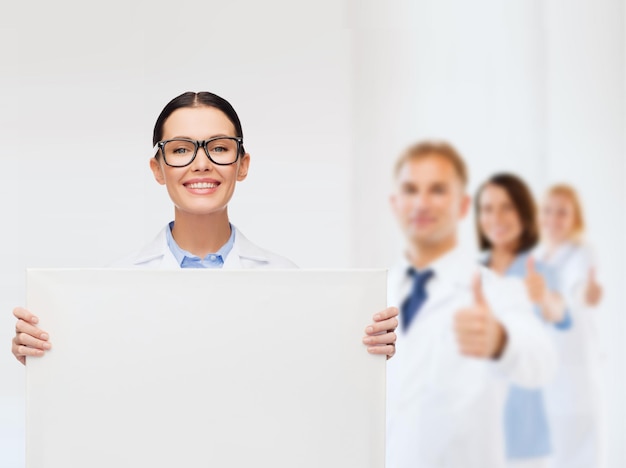 concept de soins de santé, de publicité et de médecine - femme médecin souriante à lunettes avec tableau blanc blanc