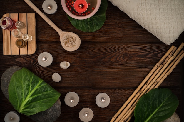 Concept de spa, composition douillette avec du sel de bain, une cuillère en bois, des pierres et des bougies sur la table en bois du salon spa avec ambiance relaxante et saine