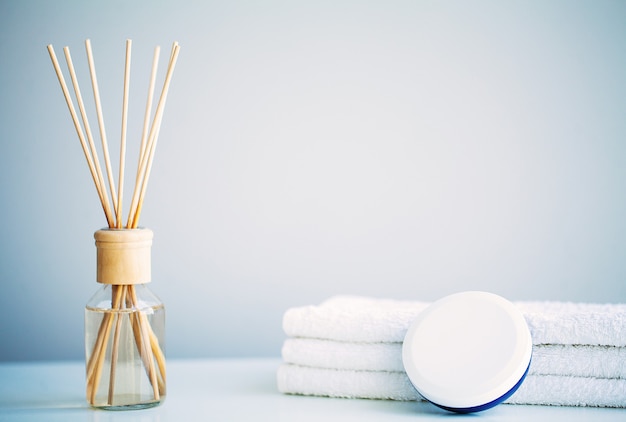 Concept de spa. Crème hydratante, serviettes et huile aromatique sur table dans la salle de bain.