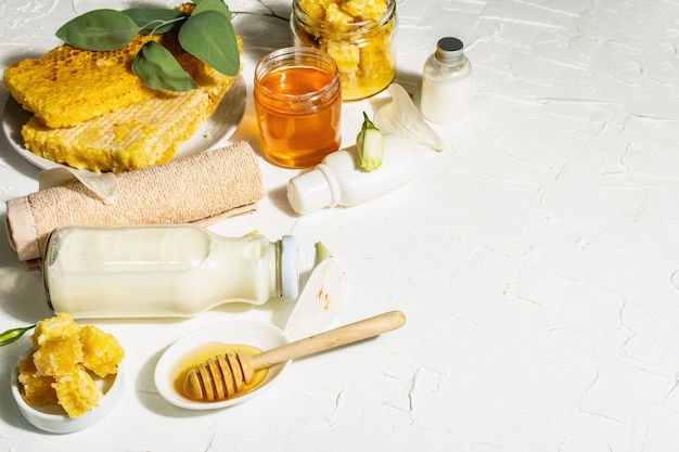 Concept de spa avec du miel et du lait. Cosmétiques naturels, ingrédients biologiques. Lumière dure, ombre sombre. Fond de mastic blanc, espace de copie