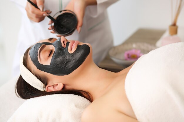 Concept de spa. Jeune femme avec masque facial nutritif dans un salon de beauté, gros plan