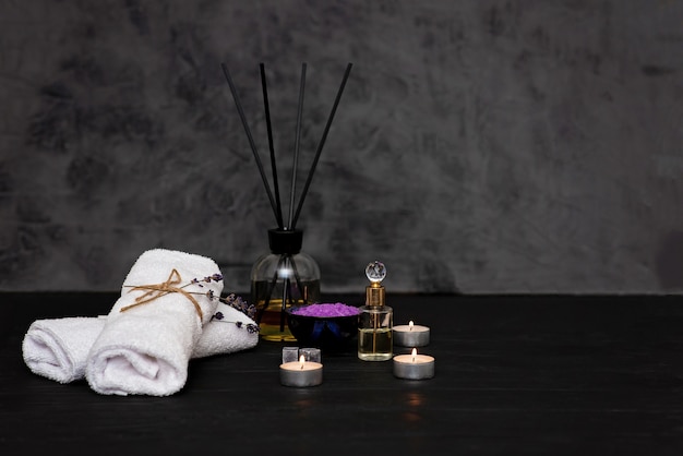 Concept de spa. Sel de lavande pour un bain relaxant, huile aromatique, bougies, serviettes blanches, fleurs de lavande sèches, parfum sur fond gris. Aromathérapie