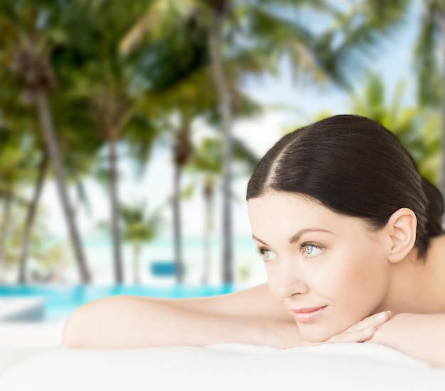 concept de spa, de vacances et de villégiature - femme souriante dans un salon de spa allongé sur le bureau de massage