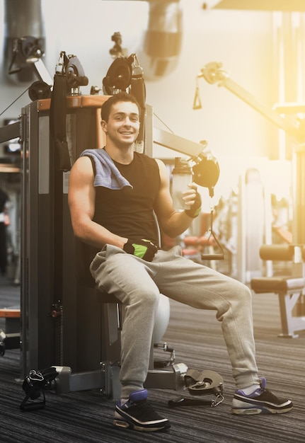 concept de sport, de fitness, d'équipement, de style de vie et de personnes - homme souriant faisant de l'exercice sur une machine de gym