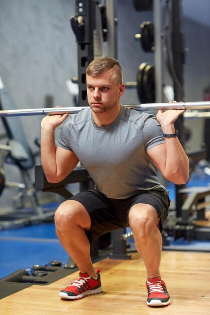 concept de sport, de fitness, de musculation, de style de vie et de personnes - jeune homme avec des muscles fléchissants d'haltères dans la salle de sport