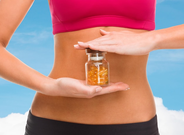 concept de sport, de fitness, de soins de santé et de régime alimentaire - gros plan de mains féminines avec une bouteille de capsules