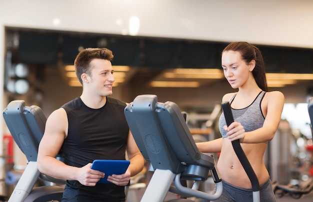 concept de sport, de fitness, de style de vie, de technologie et de personnes - femme avec entraîneur exerçant sur un stepper dans une salle de sport