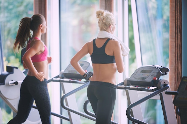 Concept de sport, fitness, style de vie, technologie et personnes - femme souriante exerçant sur tapis roulant dans la salle de gym