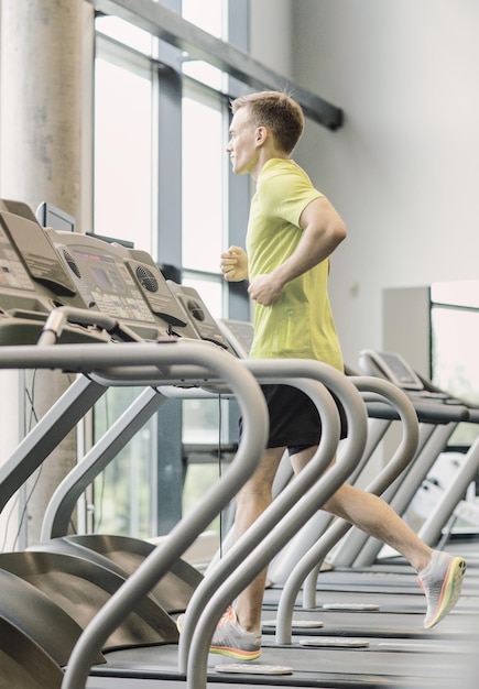 concept de sport, de fitness, de style de vie, de technologie et de personnes - homme souriant faisant de l'exercice sur un tapis roulant dans une salle de sport