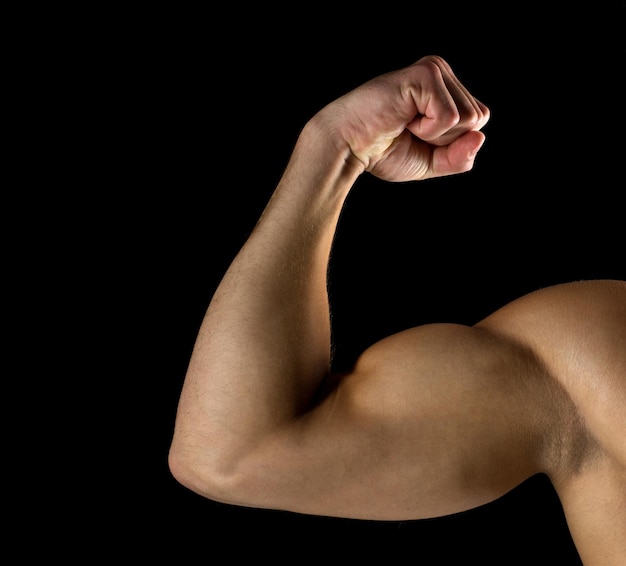 Photo concept de sport, de musculation, de force et de personnes - gros plan d'un jeune homme montrant des biceps sur fond noir