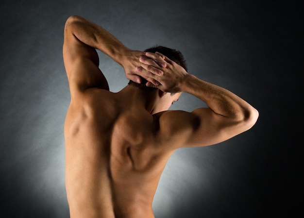 concept de sport, de musculation, de force et de personnes - jeune homme debout sur fond noir de dos