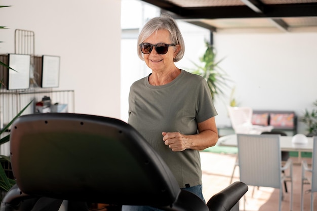 Concept de sport de personnes Heureuse femme âgée faisant des exercices de course sur tapis roulant dans la terrasse de la maison