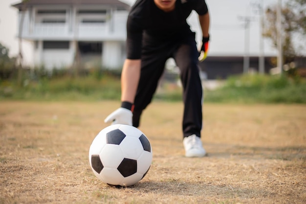 Concept de sports et de loisirs un gardien de but masculin debout devant le but en lançant une balle