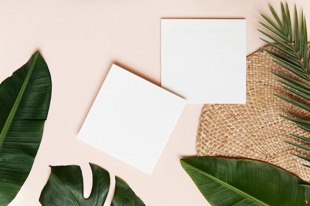 Photo concept de style flatlay, feuille de papier blanc et feuilles de palmier tropical sur mur rose