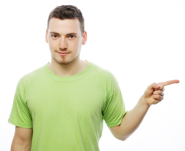 Concept de style de vie et de personnes : Un jeune homme souriant et heureux montre quelque chose sur fond blanc.