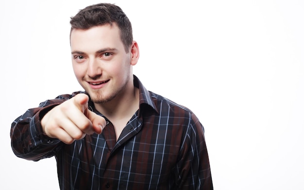 Concept de style de vie et de personnes : Un jeune homme souriant et heureux montre quelque chose sur fond blanc.